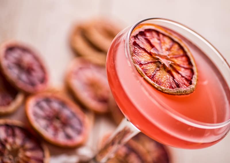 Close-up of a blood orange cocktail garnished with a dehydrated blood orange wheel