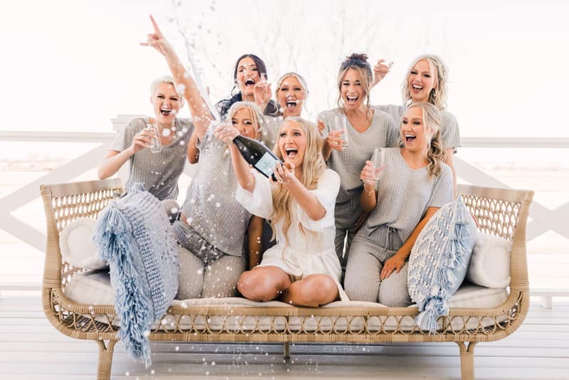 Bridesmaids in matching robes celebrating with drinks during the getting-ready hour