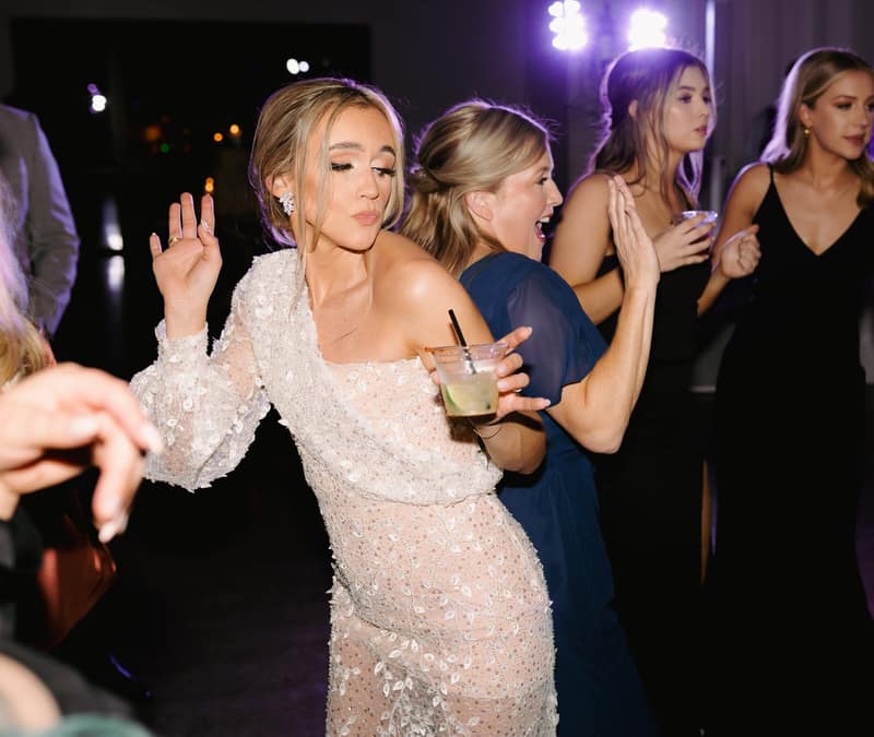 Bride holding a cocktail on the dance floor with her guests