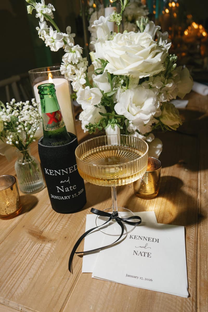 Gold champagne coupes, white florals and candlelight on a reception table