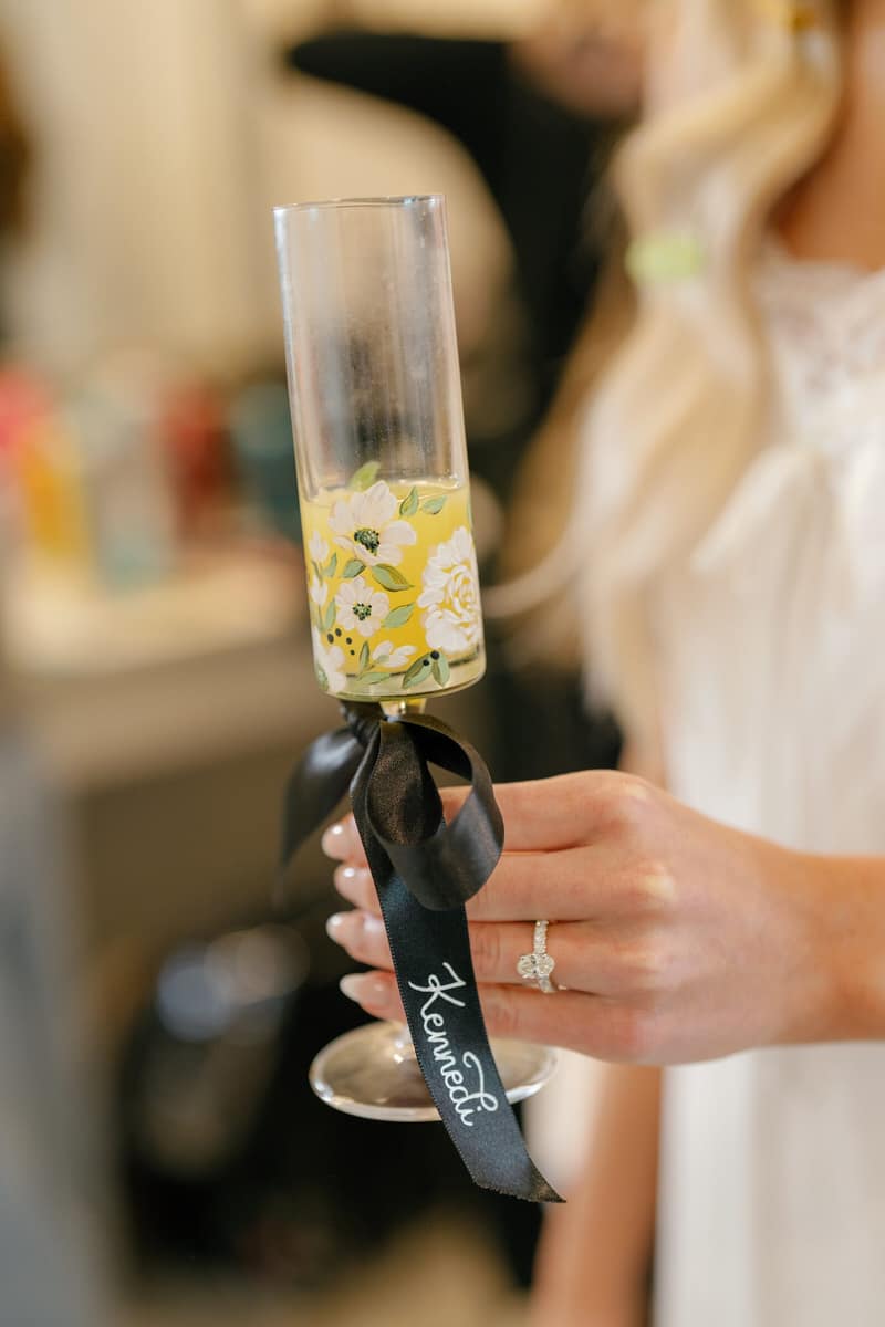 Guest holding a champagne flute tied with a ribbon