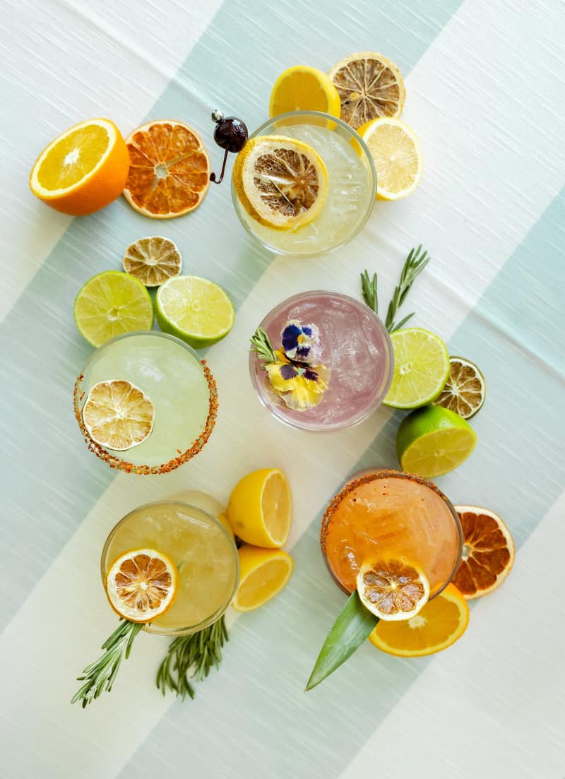 Overhead flat lay of cocktails surrounded by fresh and dehydrated citrus