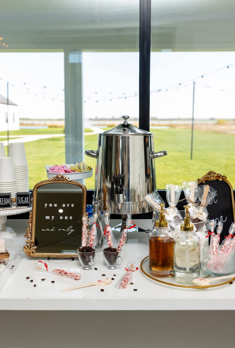 Coffee bar station with an urn and sweet treats at an outdoor wedding