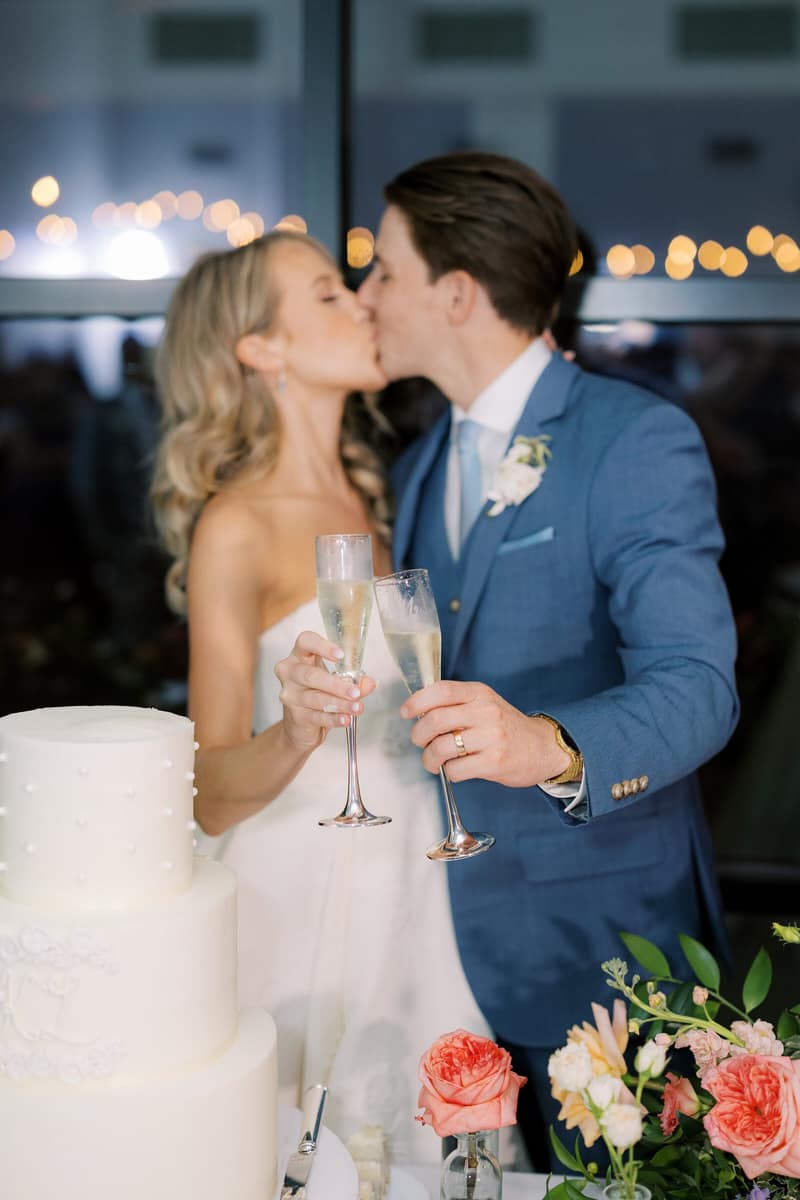 Couple kissing while holding champagne at the cake table