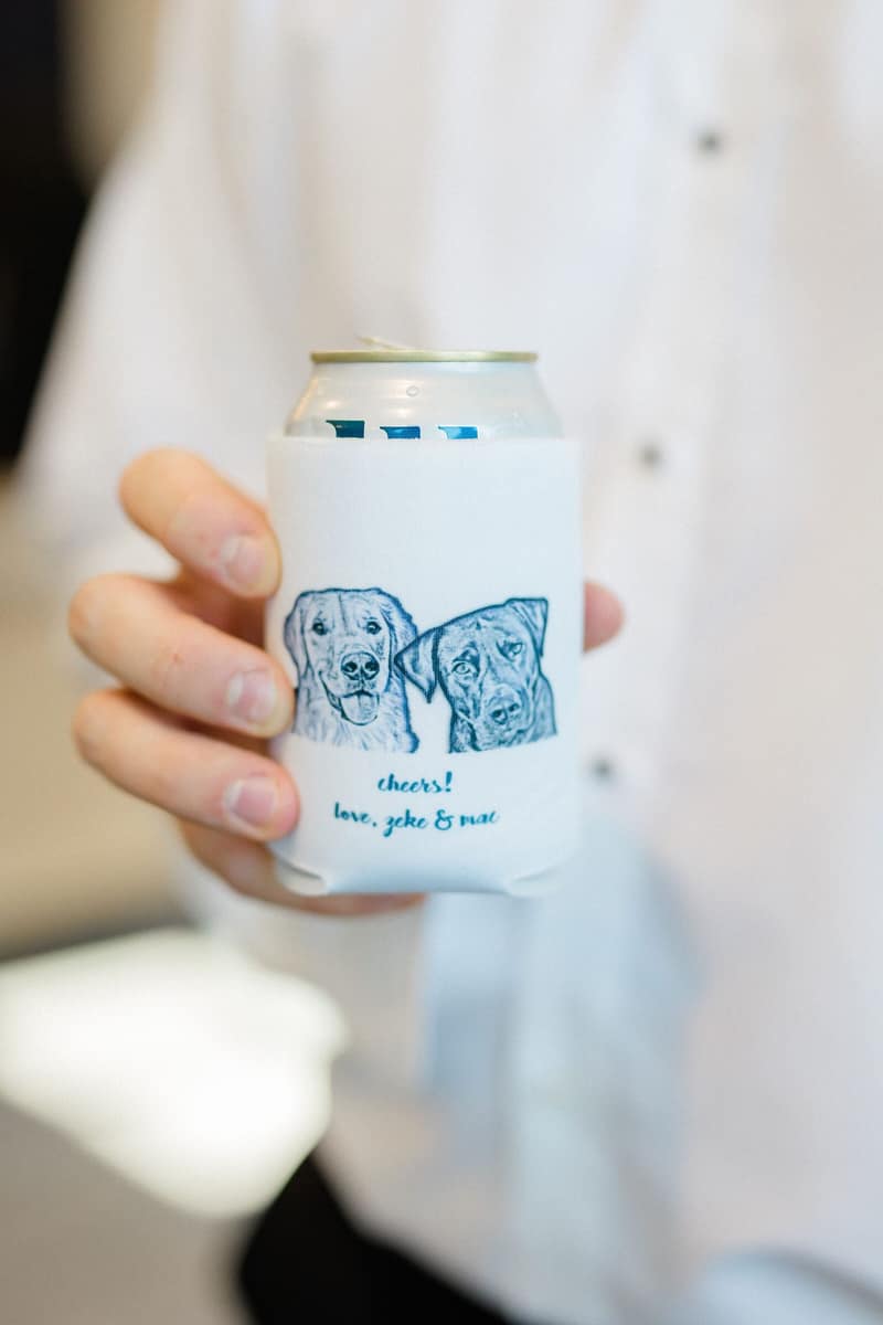 Guest holding a custom wedding koozie illustrated with the couple's dogs