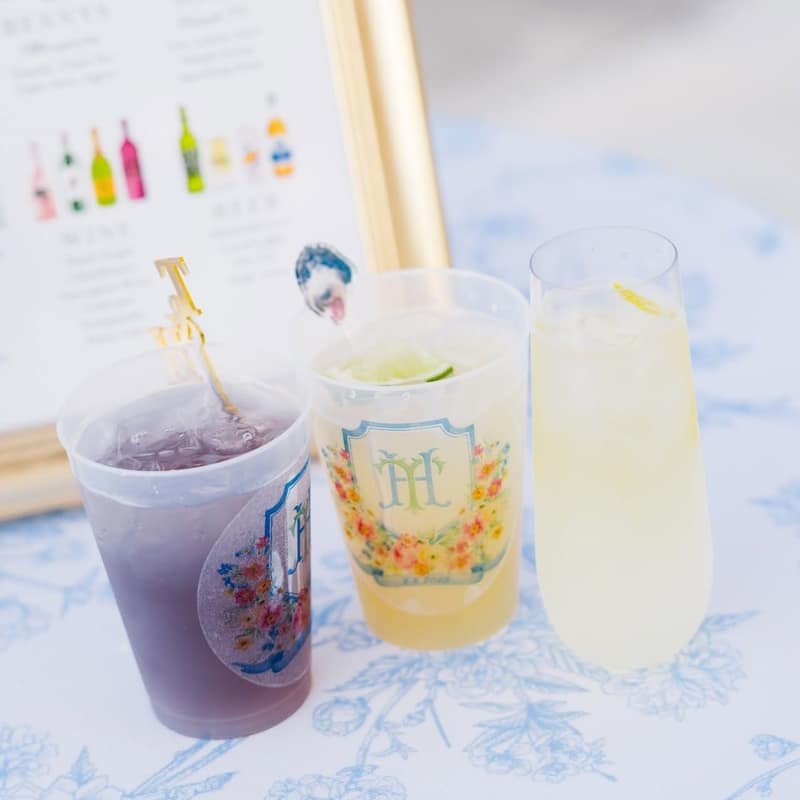 Three custom-printed cups holding a berry lemonade, a limeade and a lemonade on a blue toile table