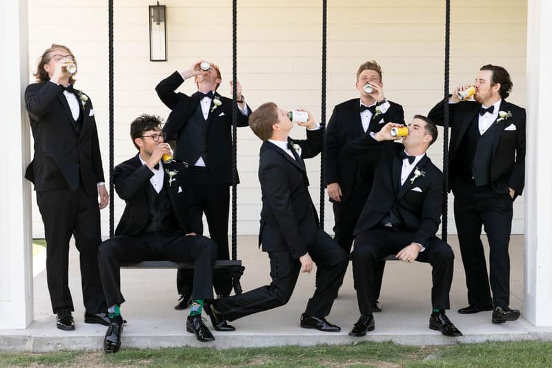 Groomsmen in tuxedos with drinks during the getting-ready hour