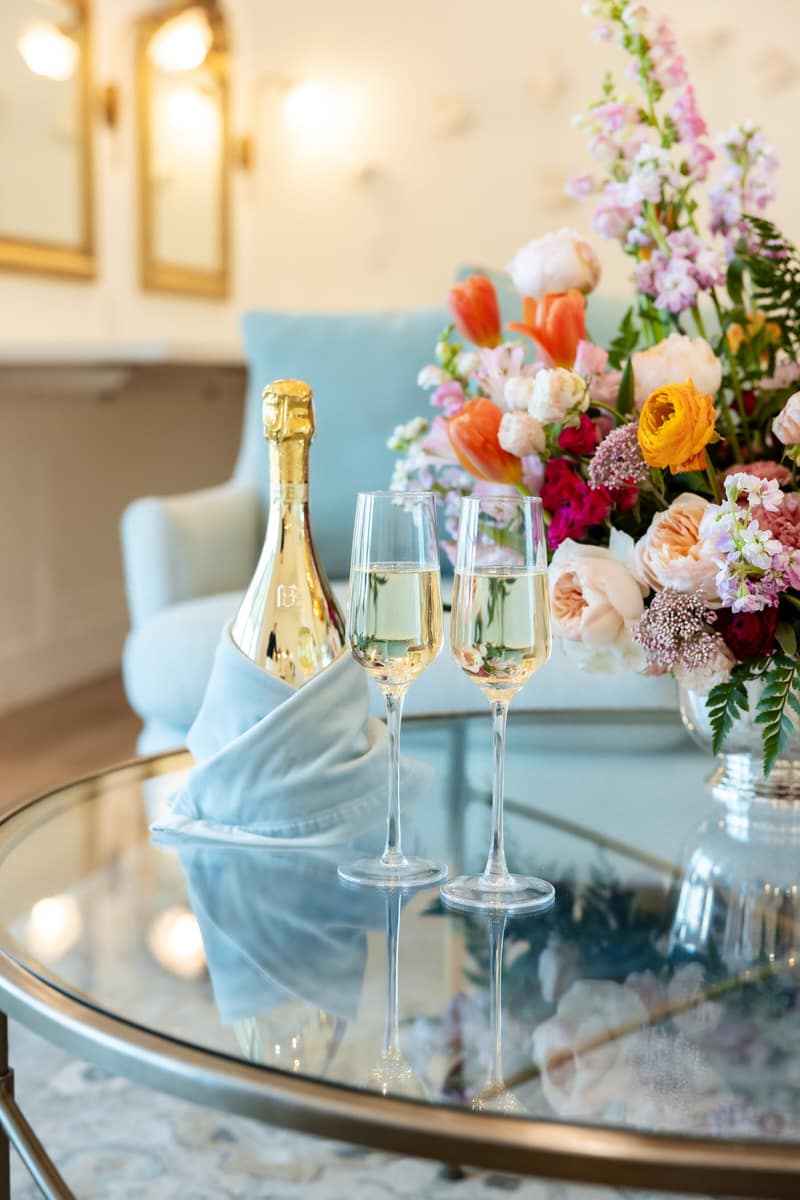 Champagne and flutes with fresh florals on a mirrored bar cart