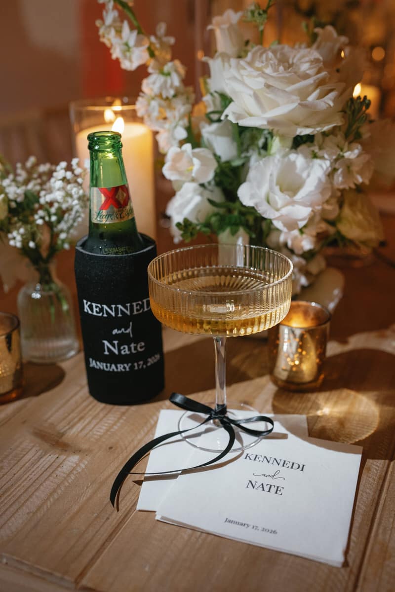 Reception place setting with a personalised koozie and gold champagne coupes