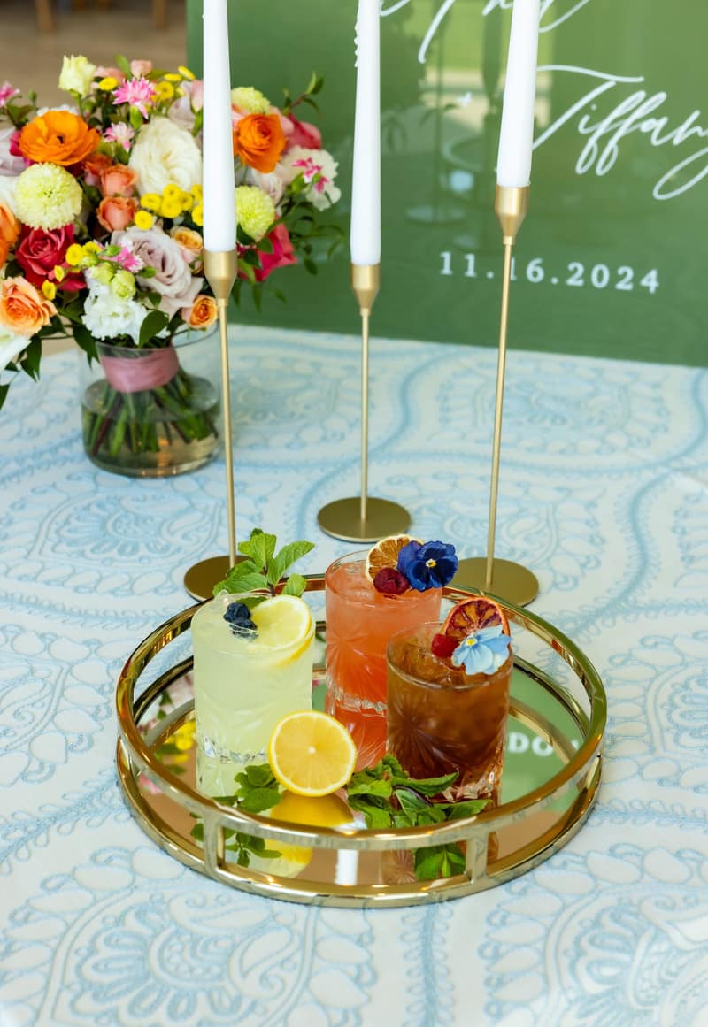 Signature cocktails on a tray beside custom wedding signage