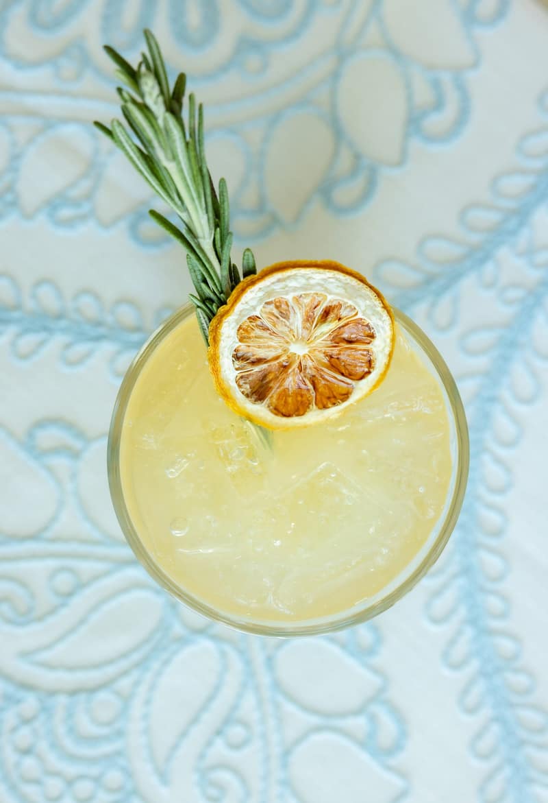 Overhead view of a specialty lemonade garnished with dehydrated citrus and rosemary