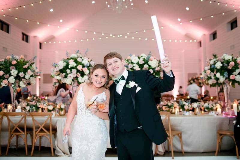 Couple with drinks in a tented wedding reception lit in pink